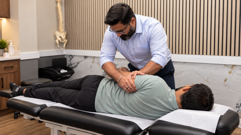 Dr. Dhillon providing chiropractic treatment to a male patient during a shoulder assessment at a Brampton clinic for rotator cuff tear treatment Brampton.